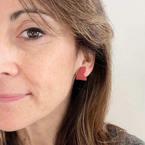 Pendiente corazón pequeño rojo puesto, pegado a la oreja