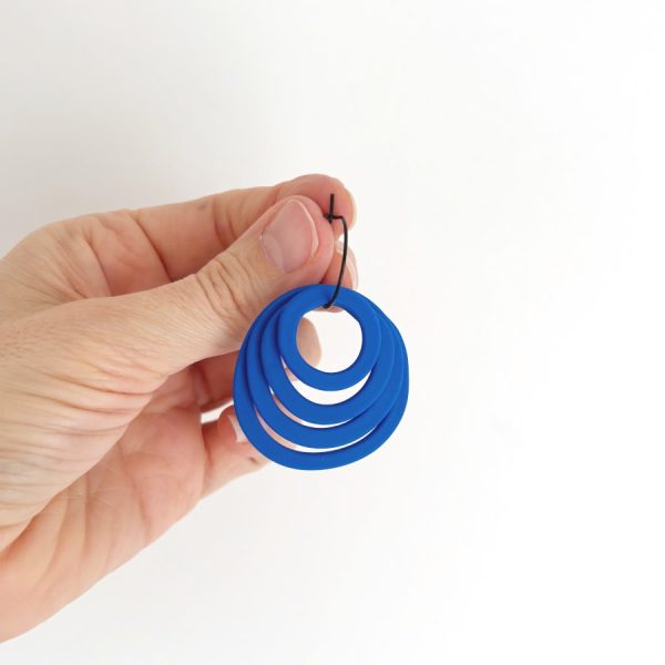 Pendientes Rosa en color azul sujetados en la mano